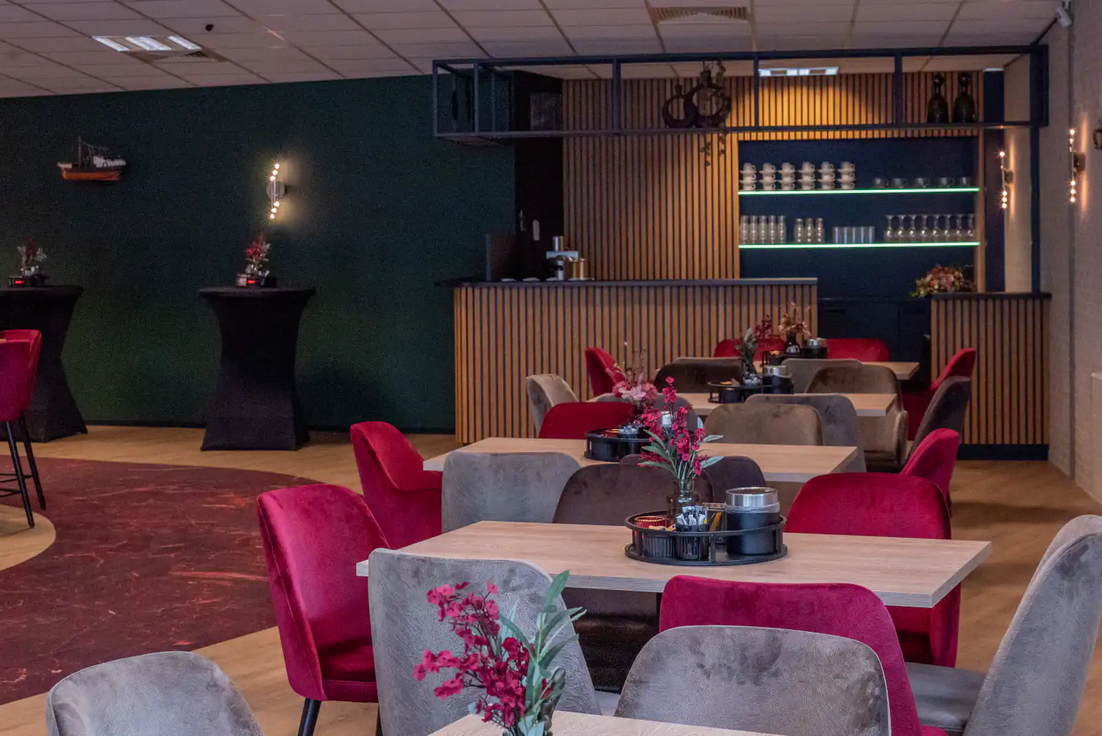 Ingerichte ontmoetingsruimte met tafels, stoelen en een koffiebar